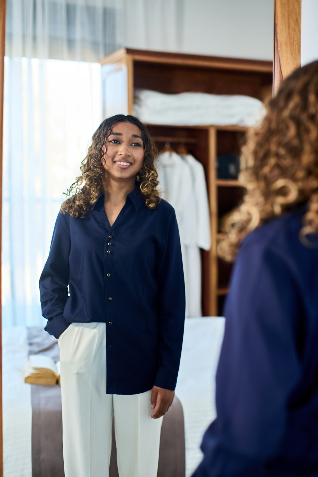 A woman in a navy shirt smiling at her reflection